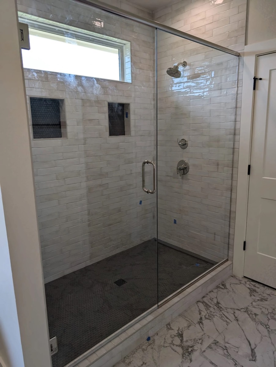 White subway-tile walk-in shower with a clear glass door and chrome hardware, installed by Bob's Shower Plus