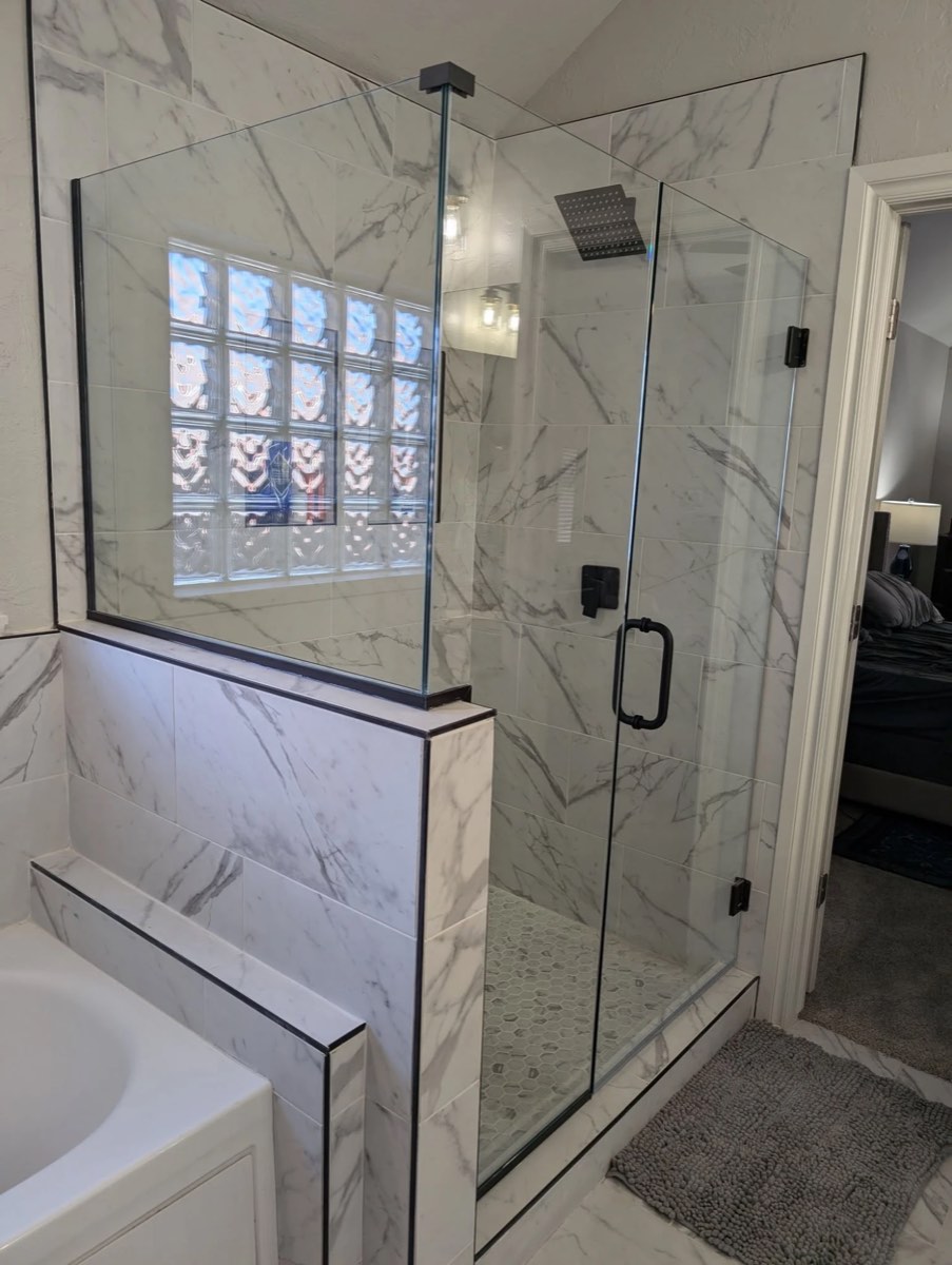 Frameless glass corner shower on a marble-look knee wall with matte black hinges, clamps and handle, installed by Bob's Shower Plus